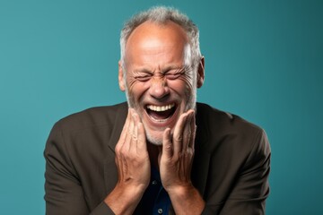 Poster - Headshot portrait photography of a grinning mature man placing the hand over the mouth in a laughter gesture against a sea-green background. With generative AI technology