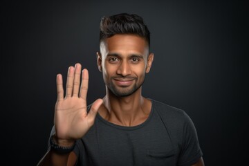 Wall Mural - Headshot portrait photography of a satisfied boy in his 30s making a no or stop gesture with the extended palm against a metallic silver background. With generative AI technology