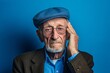 © Markus Schröder - Headshot portrait photography of a glad old man covering one's ears against a periwinkle blue background. With generative AI technology