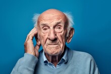 Headshot Portrait Photography Of A Glad Old Man Covering One's Ears Against A Periwinkle Blue Background. With Generative AI Technology
