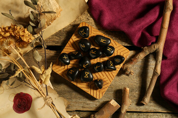 Poster - Composition with black rune stones and dried plants on wooden table, flat lay