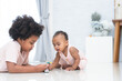 Two African kids, cute newborn 11 months baby girl and 5 years old boy, brother and sister playing together on floor, having fun with car model toy. Happy siblings relationship and education concept