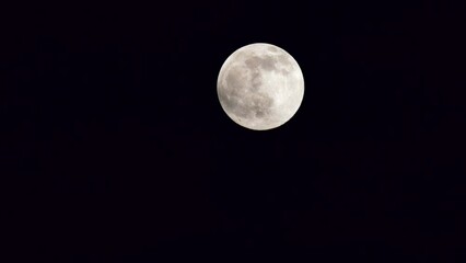 Wall Mural - bright illuminated full moon motion in natural speed, small clouds moving in front of the moon, myst