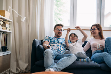 Family watches sports together and son cheers.