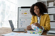 © Phimwilai - African American businesswoman searching through piles of paperwork for financial, tax, accounting documents on her desk to prepare to explain and clarify at management concept meeting.
