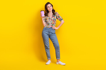 Poster - Full body photo of young thinking girl hold plastic cup coffee cappuccino look dream empty space energy isolated on yellow color background