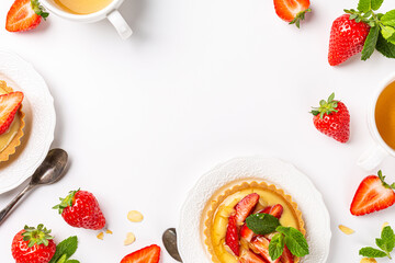 Wall Mural - Beautiful composition of small tartlet pastries with vanilla custard, topped with strawberry fruits and almond sprinkles over white background. Concept of homemade sweet pastries. Copy space, top view