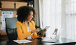 © laddawan - African Woman freelancer is working her job on computer tablet and laptop Doing accounting analysis report real estate investment data, Financial
