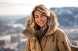 © Markus Schröder - Medium shot portrait photography of a happy girl in her 30s wearing a warm parka against a scenic mountain overlook background. With generative AI technology
