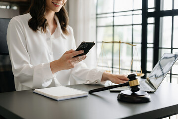 justice and law concept.Male judge in a courtroom  the gavel, working with smart phone and laptop and digital tablet computer on wood table in morning light ..