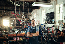 Happy, Portrait And Repair Man In Bicycle Shop With Arms Crossed In Small Business Workshop. Owner, Bike Mechanic And Smile Of Confident Person, Professional Or Mature Technician And Glasses In Store