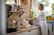 © luckybusiness - Joyful young woman washing dishes in a modern kitchen, putting plate away in a dish rack and smiling.