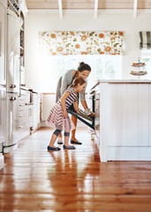 Canvas Print - Food, mother with her child baking and in the kitchen of their home with a lens flare. Happy family or bonding time, bake or cook and woman with girl at the oven prepare a meal for lunch together