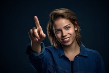 Wall Mural - Headshot portrait photography of a glad girl in her 20s raising a finger as if having an idea against a navy blue background. With generative AI technology