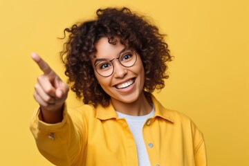 Wall Mural - Close-up portrait photography of a joyful girl in her 20s raising a finger as if having an idea against a pastel yellow background. With generative AI technology