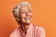 © Markus Schröder - Close-up portrait photography of a grinning mature woman covering one eye against a pastel orange background. With generative AI technology