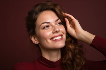 Wall Mural - Close-up portrait photography of a grinning girl in her 30s putting the hand on the forehead to look for someone in the distance against a burgundy red background. With generative AI technology
