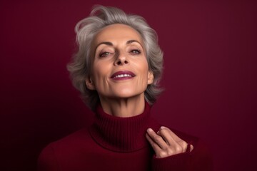 Canvas Print - Close-up portrait photography of a satisfied mature woman blowing air kisses at camera against a burgundy red background. With generative AI technology