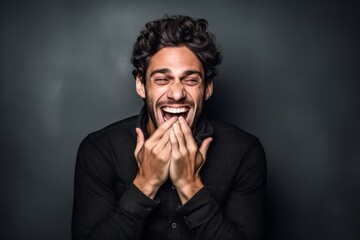 Poster - Headshot portrait photography of a beautiful boy in his 30s placing the hand over the mouth in a laughter gesture against a metallic silver background. With generative AI technology