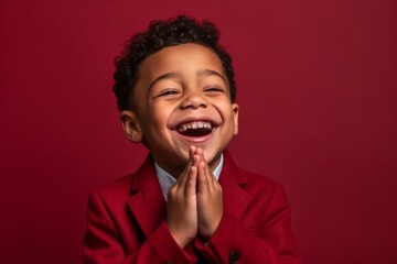 Poster - Medium shot portrait photography of a happy kid male placing the hand over the mouth in a laughter gesture against a ruby red background. With generative AI technology