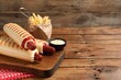 © New Africa - Delicious french hot dogs, fries and dip sauce on wooden table. Space for text