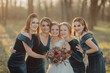 Bride with bridesmaids on the park on the wedding day. Bridesmaids in blue dresses and bride holding beautiful bouquets. Beautiful luxury wedding blog concept. Summer wedding.