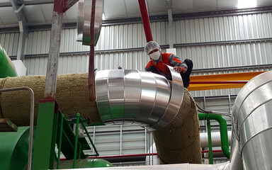 Steam piping insulation installation work by an insulation worker for the steam turbine biomass power plant.