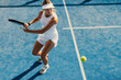 © Jacob Lund - Sportswoman playing with powerful strokes in a padel court