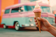 Hand holding a cone with ice-cream in pastel colours with a ice cream truck in background