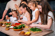 © dvulikaia - Four little girls prepare a vegetarian salad under the supervision of adults.