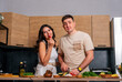 © dvulikaia - Young married couple cooking dinner at the kitchen.