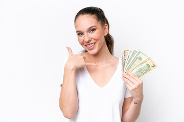 Wall Mural - Young caucasian woman taking a lot of money isolated on white background making phone gesture. Call me back sign