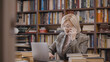 © Synthex - Busy woman in her 50s talking on the phone and working on her laptop in her home study