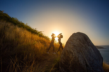 .Two women exercising on the top of a mountain..On the hilltop filled with the smell of the sea, .making it the perfect place to exercise relax and enjoy the scenery..golden sunrise shines background.