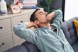 © Krakenimages.com - Young hispanic man relaxed with hands on head sitting on sofa at home