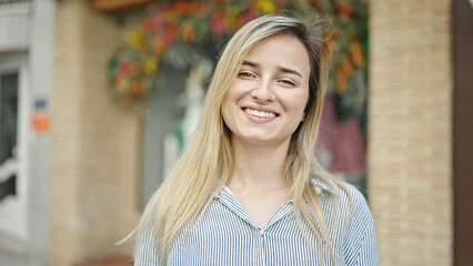 Wall Mural - Young blonde woman smiling confident standing at street