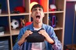 Young hispanic man wearing virtual reality glasses angry and mad screaming frustrated and furious, shouting with anger looking up.