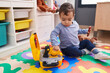 © Krakenimages.com - Adorable hispanic boy playing with tools toy sitting on floor at kindergarten