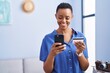 © Krakenimages.com - African american woman using smartphone and credit card standing at home