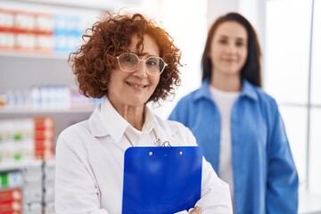 Wall Mural - Two women pharmacist and customer smiling confident standing at pharmacy