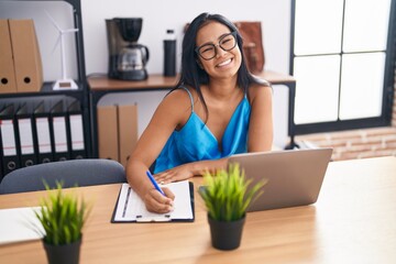 Poster - Young beautiful latin woman business worker using laptop writing on document at office