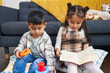© Krakenimages.com - Adorable boy and girl playing with hoops game reading book at home