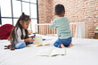 © Krakenimages.com - Adorable boy and girl drawing on notebook sitting on bed at bedroom