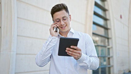 Poster - Young hispanic man talking on smartphone using touchpad at hospital