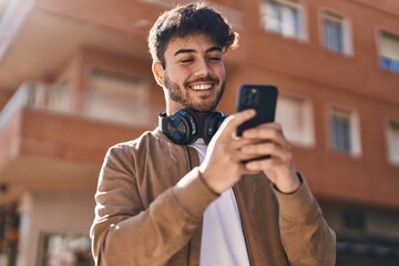 Sticker - Young hispanic man smiling confident using smartphone at street