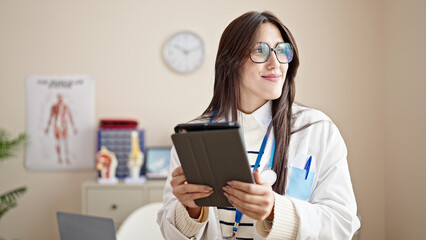 Poster - Young beautiful hispanic woman doctor using touchpad working at clinic