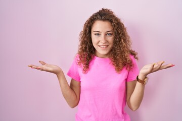 Canvas Print - Young caucasian woman standing over pink background smiling cheerful offering hands giving assistance and acceptance.