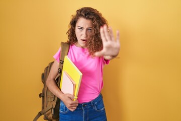 Sticker - Young caucasian woman wearing student backpack and holding books doing stop gesture with hands palms, angry and frustration expression