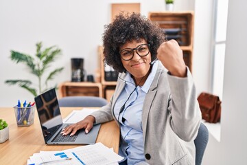 Sticker - Black woman with curly hair wearing call center agent headset at the office angry and mad raising fist frustrated and furious while shouting with anger. rage and aggressive concept.