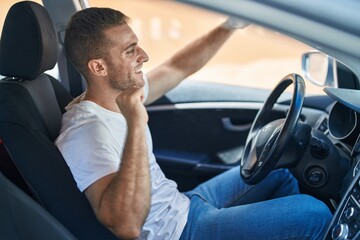 Wall Mural - Young caucasian man sitting on car dancing at street